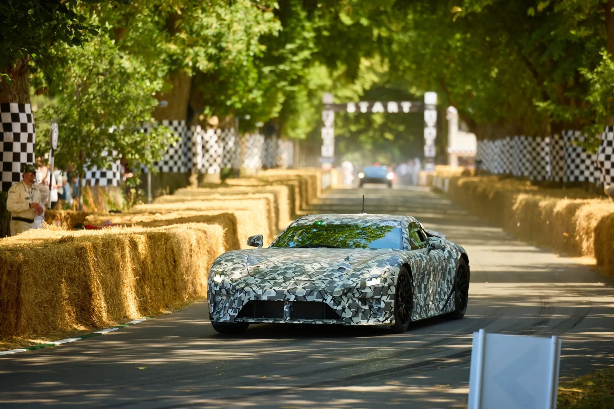 Kamuflaažiga varjatud Lexus LFA Gazoo Racing sportauto prototüüp sõitmas heinapallidega ääristatud rajal