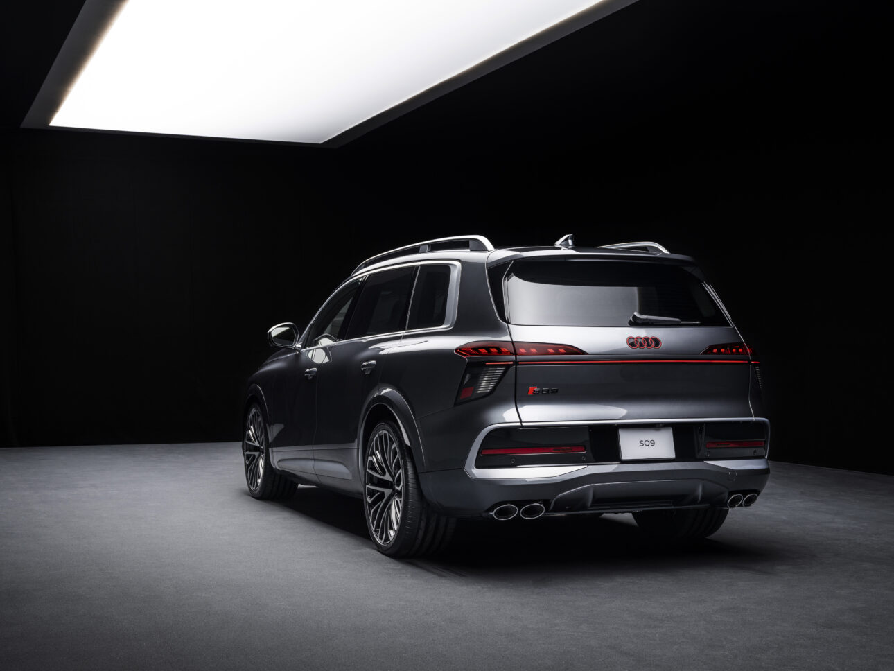 Tumehall Audi SQ9 tagumine külgvaade stuudiovalguses koos valgustatud Audi logo ja SQ9 tähisega