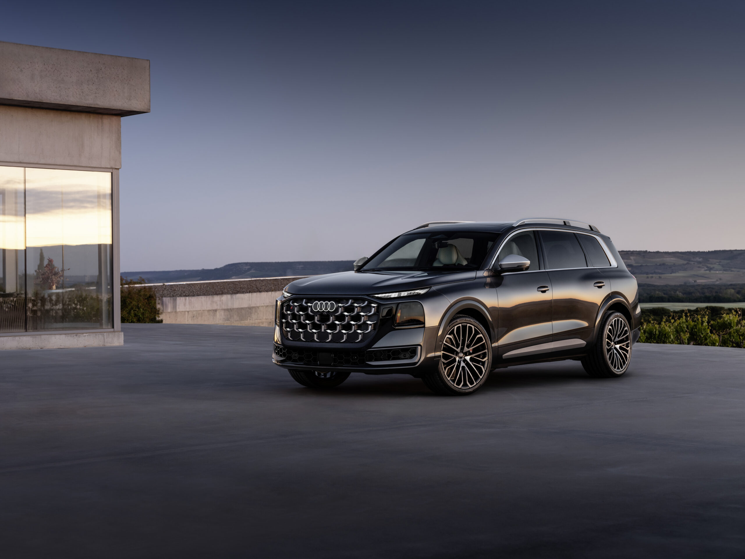 Tumehall Audi SQ9 pargitud modernse hoone ette päikeseloojangul