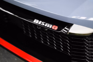 Hõbedane NISMO logo punase O-tähega spordiauto mustal esivõrel