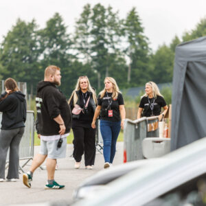 Augustfest 2026 tiimiliikmed ja korraldajad mustades Augustfest särkides kõndimas Porsche Ringi boksiteel festivali paddock-alal