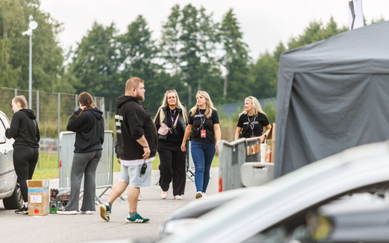 Augustfest 2026 tiimiliikmed ja korraldajad mustades Augustfest särkides kõndimas Porsche Ringi boksiteel festivali paddock-alal
