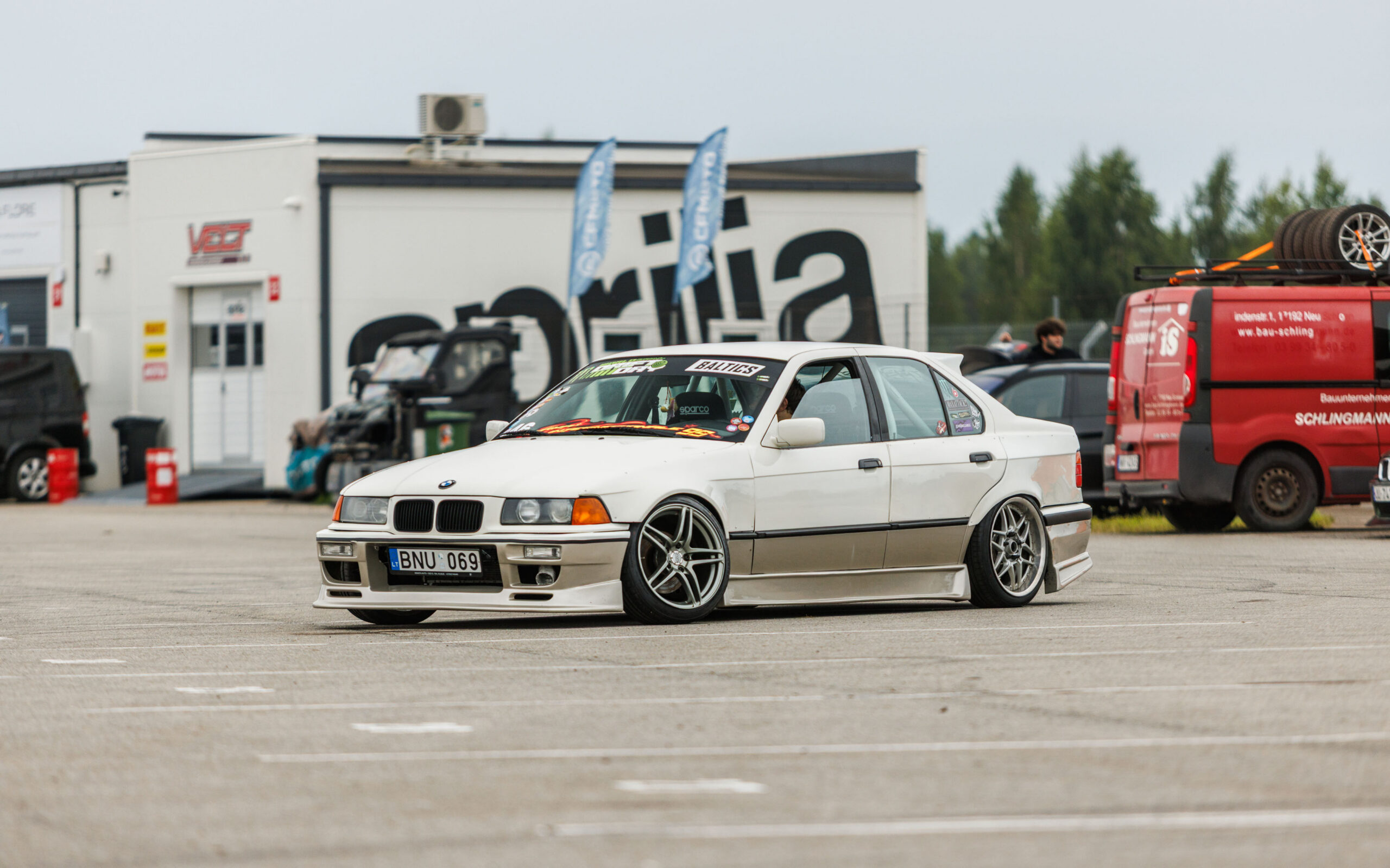 Valge madaldatud kahetoonilise kerekomplektiga BMW E36 sedaan driftiauto sõitmas Porsche Ringi boksiteel Augustfest 2026 festivalil