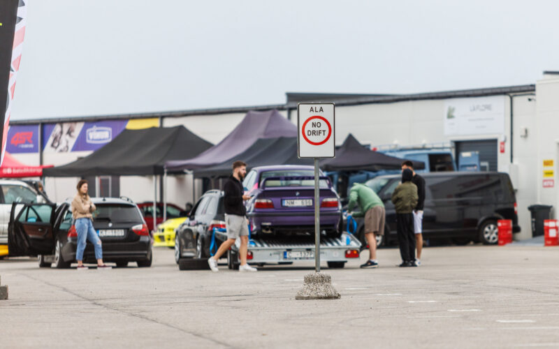 Liiklusmärk ALA NO DRIFT Porsche Ringi boksiteel ja taustal treileril olev lilla BMW E36 driftiauto Augustfest 2026 festivalil