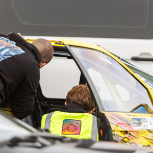 Tiimi mehaanikud kollase BMW E36 PRO2 driftiauto salongi ette valmistamas Porsche Ringi boksiteel Augustfest 2026 festivalil