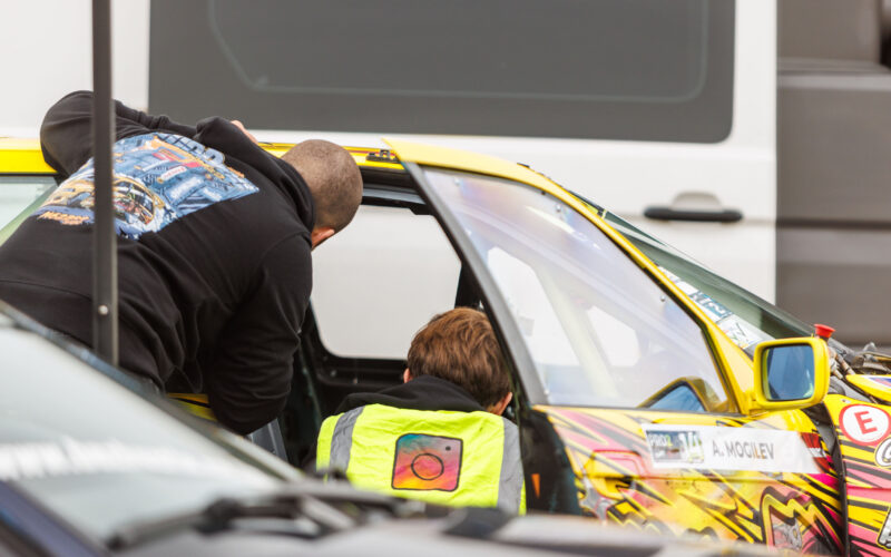 Tiimi mehaanikud kollase BMW E36 PRO2 driftiauto salongi ette valmistamas Porsche Ringi boksiteel Augustfest 2026 festivalil