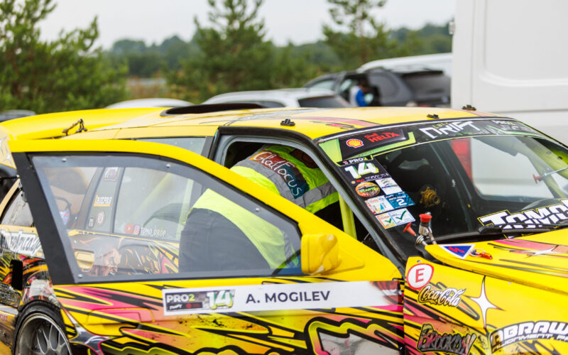 Tehnik kollases helkurvestis ette valmistamas kollast BMW E36 PRO2 driftiautot võistlussõiduks Porsche Ringi paddock-alal Augustfest 2026 festivalil