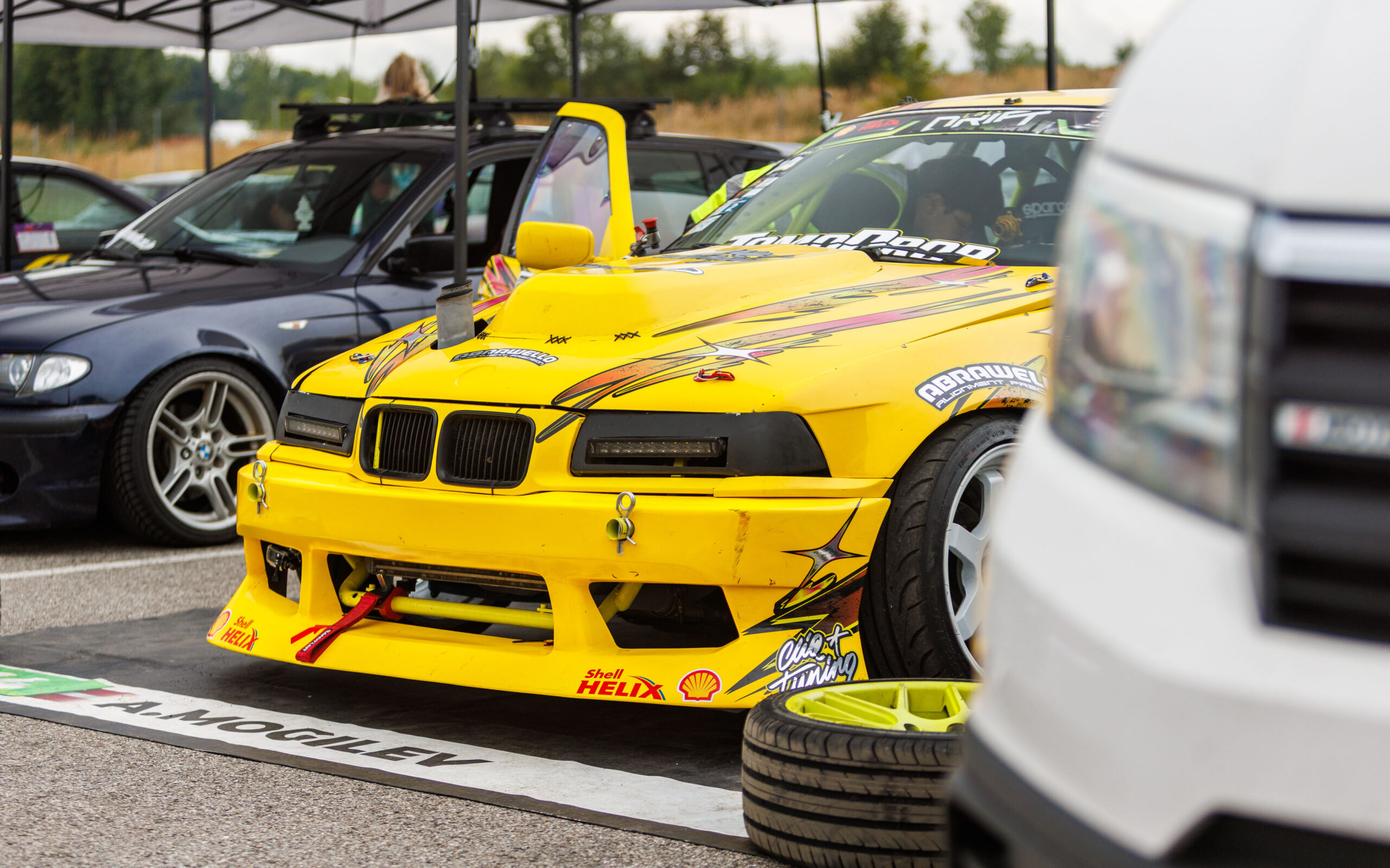Kollane BMW E36 driftiauto laiendatud kere ja Shell Helix kleepsudega Porsche Ringi hooldustelgis Augustfest 2026 festivalil