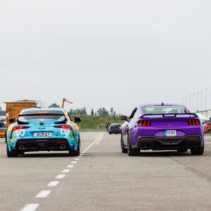 Tagantvaates kirju disainkilega Toyota GR Supra ja lilla Ford Mustang S650 kõrvuti sõitmas Porsche Ringi boksiteel Augustfest 2026 festivalil