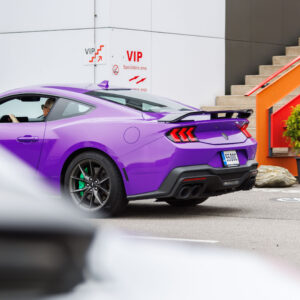 Lilla Ford Mustang S650 sportauto tagantvaates roheliste pidurisadulate ja tagaspoileriga Porsche Ringi VIP ala treppide ees Augustfest 2026 festivalil