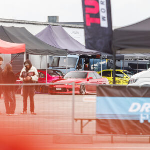 Punane madaldatud Toyota Soarer või Lexus SC driftiauto meeskonnatelkide ees Porsche Ringi paddock-alal Augustfest 2026 festivalil