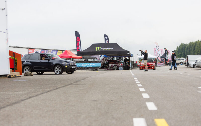 Must BMW X5 maastur seismas Porsche Ringi boksiteel Monster Energy Drift Taxi ala ja fotograafi ees Augustfest 2026 festivalil