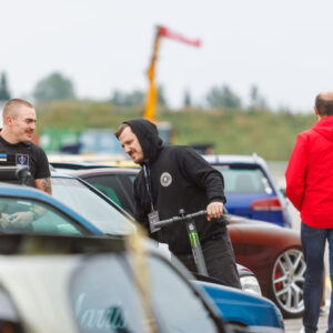 Augustfest korraldustiimi liige tõukerattaga vestlemas turvatöötajaga näituseautode vahel Pärnu Porsche Ringil Augustfest 2026 festivalil