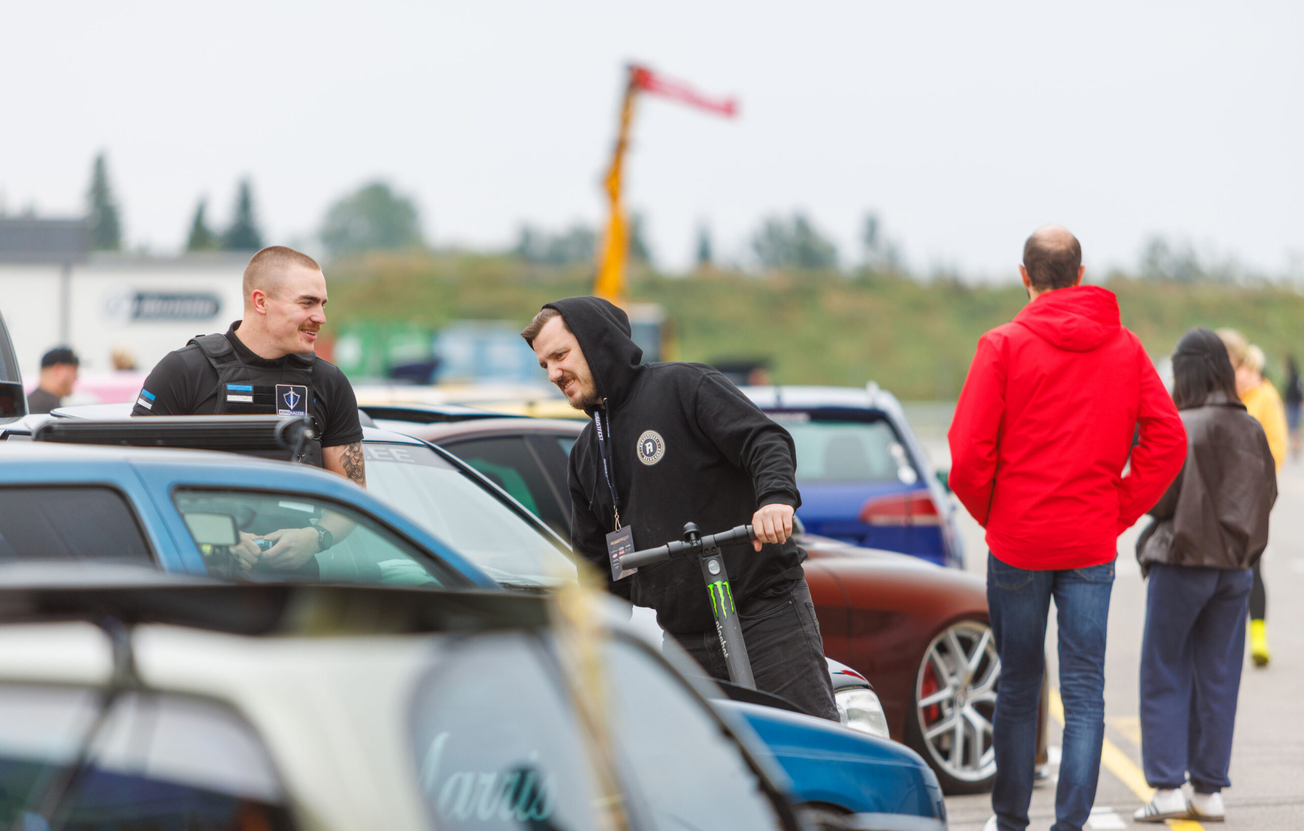 Augustfest korraldustiimi liige tõukerattaga vestlemas turvatöötajaga näituseautode vahel Pärnu Porsche Ringil Augustfest 2026 festivalil