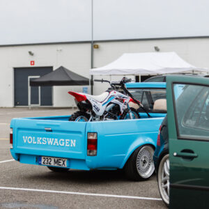 Tagantvaade helesinisest madaldatud Volkswagen Caddy MK1 kastiautost krossimootorrattaga kastis Porsche Ringi boksiteel Augustfest 2026 festivalil