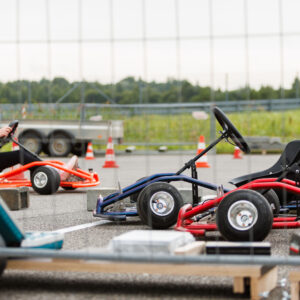 Kardisõitja kiivriga oranžis kardis rajal ja teised kardid aia taga ootel Pärnu Porsche Ringil Augustfest 2026 festivalil