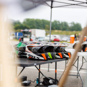 Rivi motokiivreid ja rajakiivreid laual Porsche Ringi telgi all Augustfest 2026 festivalil