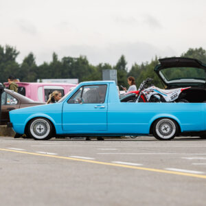 Madaldatud helesinine Volkswagen Caddy MK1 kastiauto klassikaliste kärgvelgedega ja krossitsikliga kastis Porsche Ringi näitusealal Augustfest 2026 festivalil