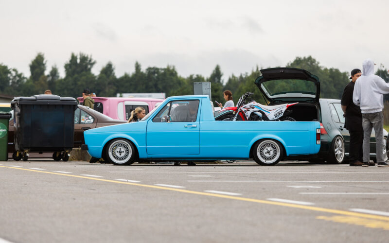 Madaldatud helesinine Volkswagen Caddy MK1 kastiauto klassikaliste kärgvelgedega ja krossitsikliga kastis Porsche Ringi näitusealal Augustfest 2026 festivalil