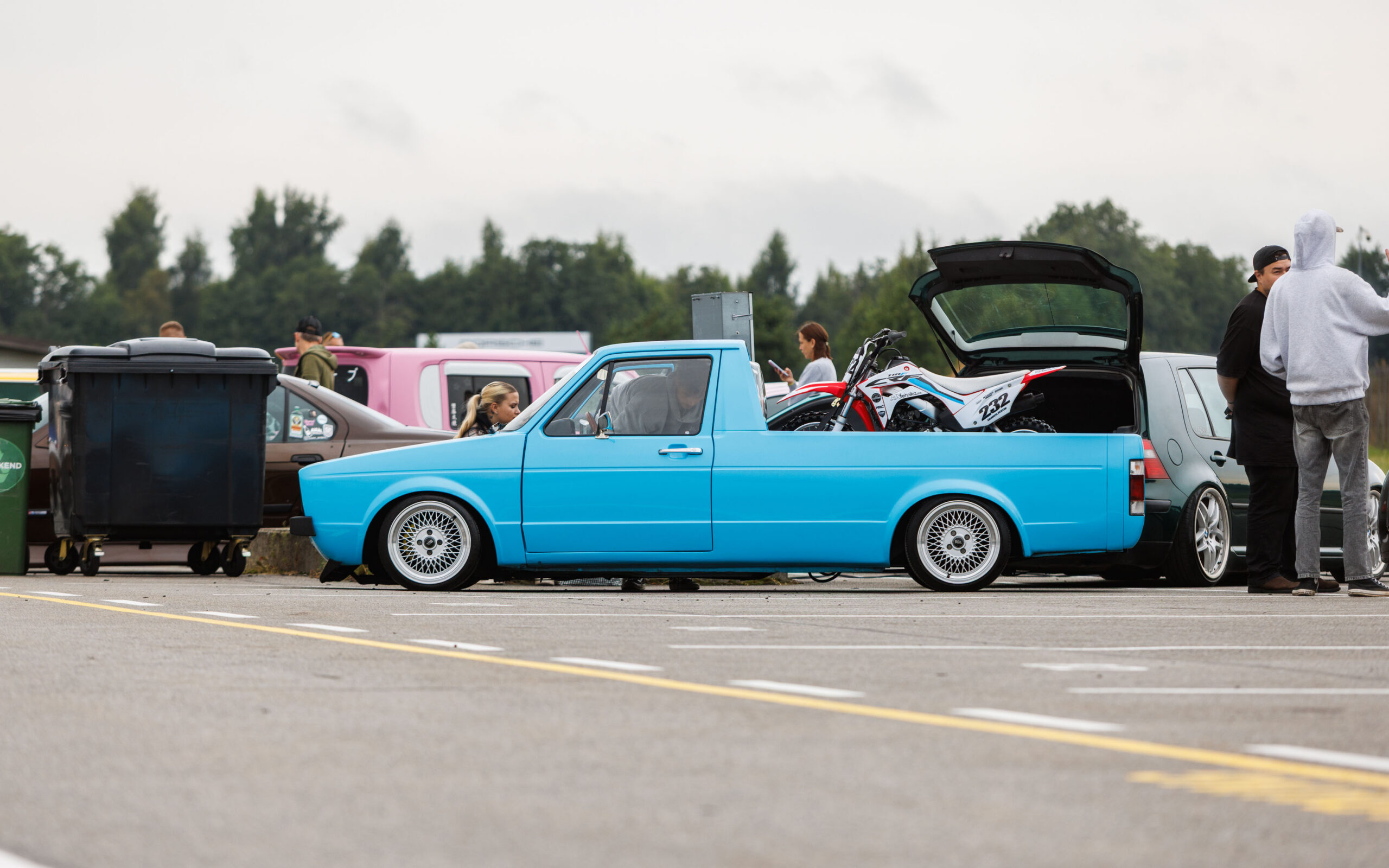 Madaldatud helesinine Volkswagen Caddy MK1 kastiauto klassikaliste kärgvelgedega ja krossitsikliga kastis Porsche Ringi näitusealal Augustfest 2026 festivalil