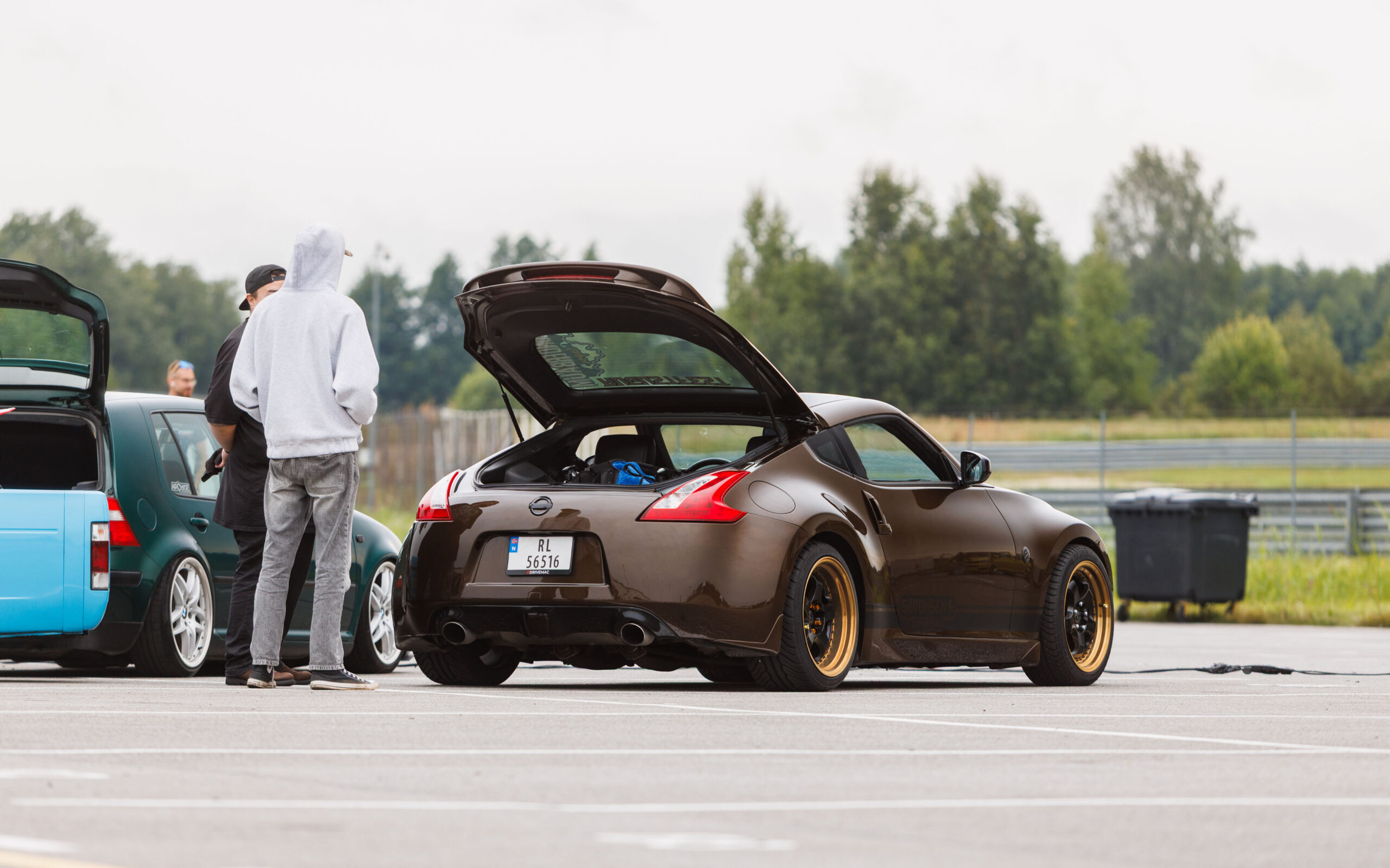 Pronkspruun madaldatud Nissan 370Z sportauto avatud tagaluugi ja kuldse randiga valuvelgedega Porsche Ringi näitusealal Augustfest 2026 festivalil