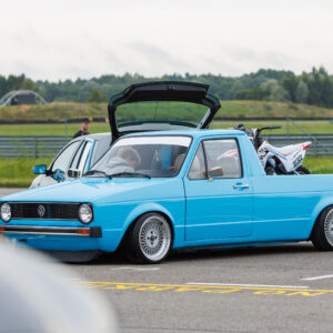 Helesinine madaldatud Volkswagen Caddy MK1 kastiauto klassikaliste kärgvelgedega, kastis krossimootorratas, Pärnu Porsche Ringi näitusealal Augustfest 2026 festivalil