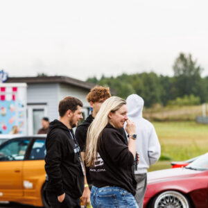 Festivalikülastajad ja noored suhtlemas oranži ja punase tuunitud auto taustal Pärnu Porsche Ringil Augustfest 2026 festivalil