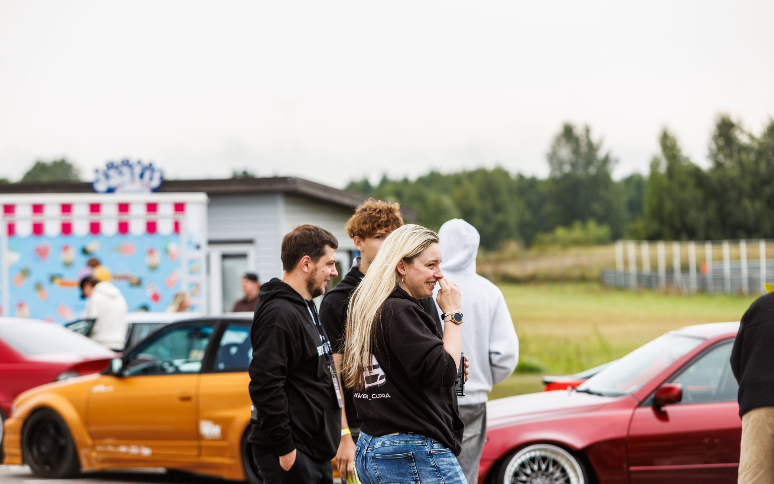 Festivalikülastajad ja noored suhtlemas oranži ja punase tuunitud auto taustal Pärnu Porsche Ringil Augustfest 2026 festivalil