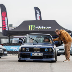 Tumesinine madaldatud BMW E30 sedaan numbrimärgiga OD-1678 seismas boksiteel Monster Energy telgi ees Porsche Ringil Augustfest 2026 festivalil