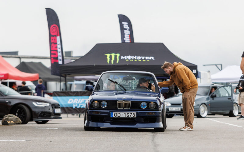 Tumesinine madaldatud BMW E30 sedaan numbrimärgiga OD-1678 seismas boksiteel Monster Energy telgi ees Porsche Ringil Augustfest 2026 festivalil