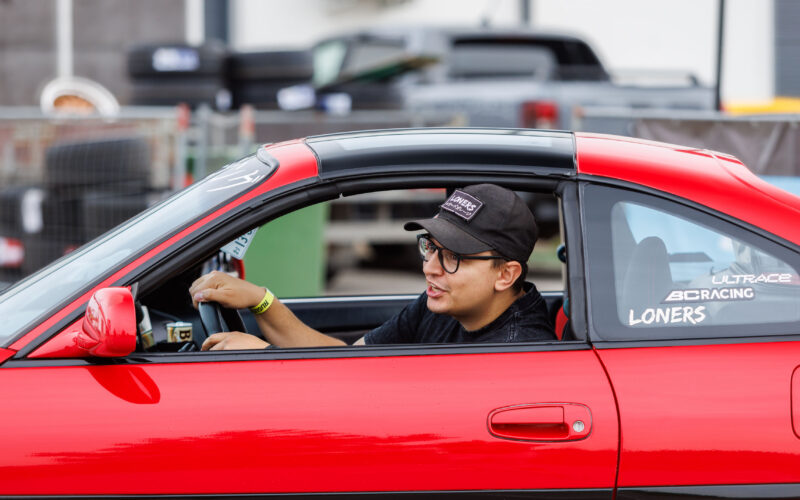 Punase sportauto roolis noormees nokamütsi ja prillidega sõitmas Porsche Ringi boksiteel Augustfest 2026 festivalil Pärnus