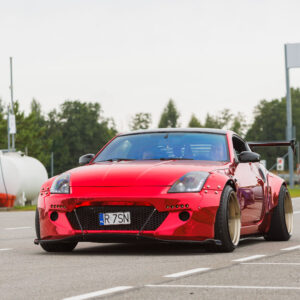 Punane kroomitud laia kerega Nissan 350Z sportauto neetitud tiivalaiendite ja sügava servaga valuvelgedega sõitmas Porsche Ringil Augustfest 2026 festivalil
