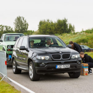 Must maastur BMW X5 E53 vedamas treileril helerohelist Volkswagen Caddy pikapi Monster Energy lipu kõrval Pärnu Porsche Ringil Augustfest 2026 festivalil