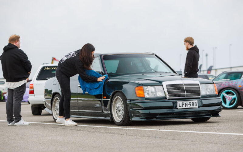 Tumesinine klassikaline madaldatud Mercedes-Benz W124 sedaan kärgvelgedega, mida naine mikrokiudlapiga puhastab Pärnu Porsche Ringil Augustfest 2026 festivalil