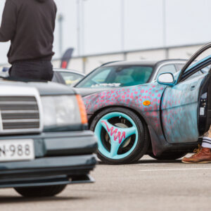 Kirju kohandatud värvkatte ja helesiniste kolme kodaraga velgedega tuuningauto tumeda klassikalise Mercedes-Benzi kõrval Pärnu Porsche Ringil Augustfest 2026 festivalil