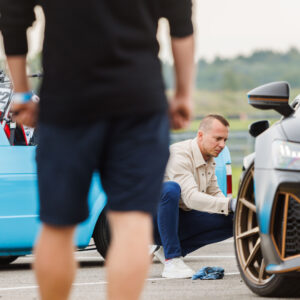 Mees kükitamas ja puhastamas mattmusta Audi RS6 pronksikarva esivelge näitusealal Pärnu Porsche Ringil Augustfest 2026 festivalil