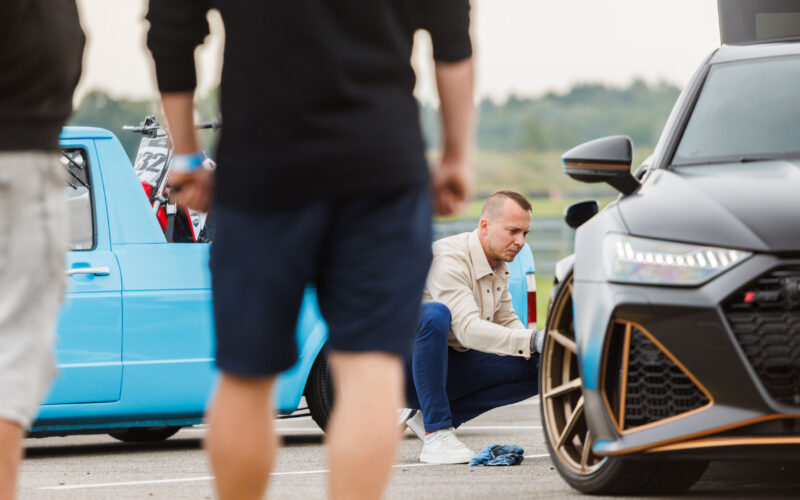Mees kükitamas ja puhastamas mattmusta Audi RS6 pronksikarva esivelge näitusealal Pärnu Porsche Ringil Augustfest 2026 festivalil
