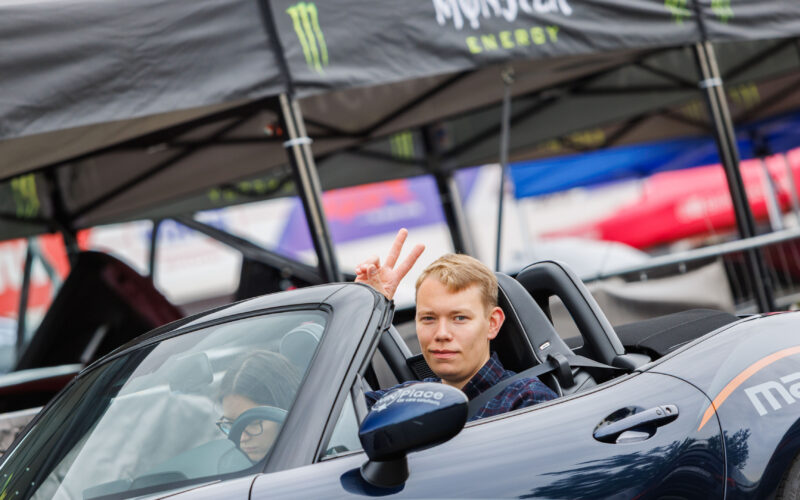 Naeratav noormees lahtise Mazda MX-5 kabrioleti roolis näitamas rahumärki Pärnu Porsche Ringil Augustfest 2026 festivalil