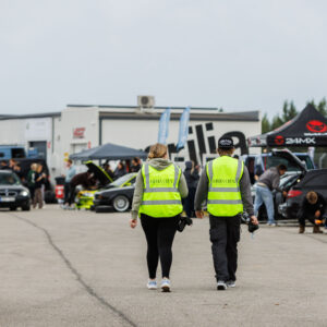 Meediameeskonna liikmed helkurvestides kõndimas Pärnu Porsche Ringi boksiteel Augustfest 2026 festivalil