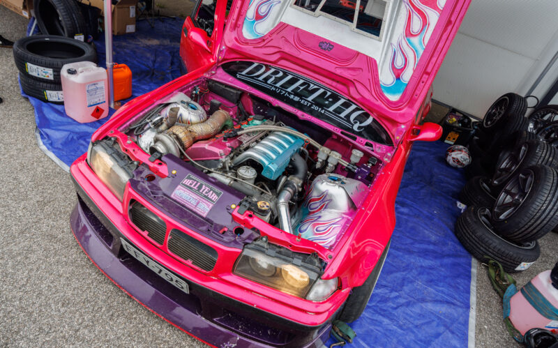 Roosa tuunitud BMW E36 driftiauto avatud mootoriruum turbomootori ja eritellimusel leegigraafikaga Pärnu Porsche Ringil Augustfest 2026 festivalil