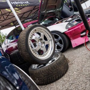 Driftiauto varurattad esiplaanil ja avatud kapotiga roosa BMW E36 driftiauto Monster Energy telgi all Pärnu Porsche Ringil Augustfest 2026 festivalil