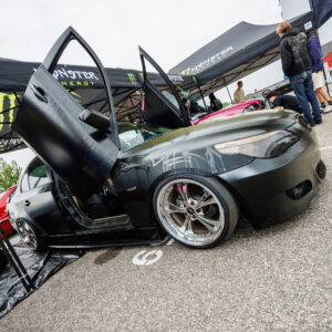Madaldatud mattmust BMW E60 sedaan ülesavanevate lambo-ustega ja kroomitud valuvelgedega Monster Energy telgi all Pärnu Porsche Ringil Augustfest 2026 festivalil