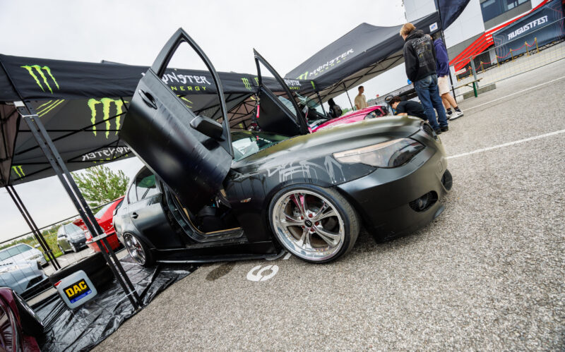 Madaldatud mattmust BMW E60 sedaan ülesavanevate lambo-ustega ja kroomitud valuvelgedega Monster Energy telgi all Pärnu Porsche Ringil Augustfest 2026 festivalil