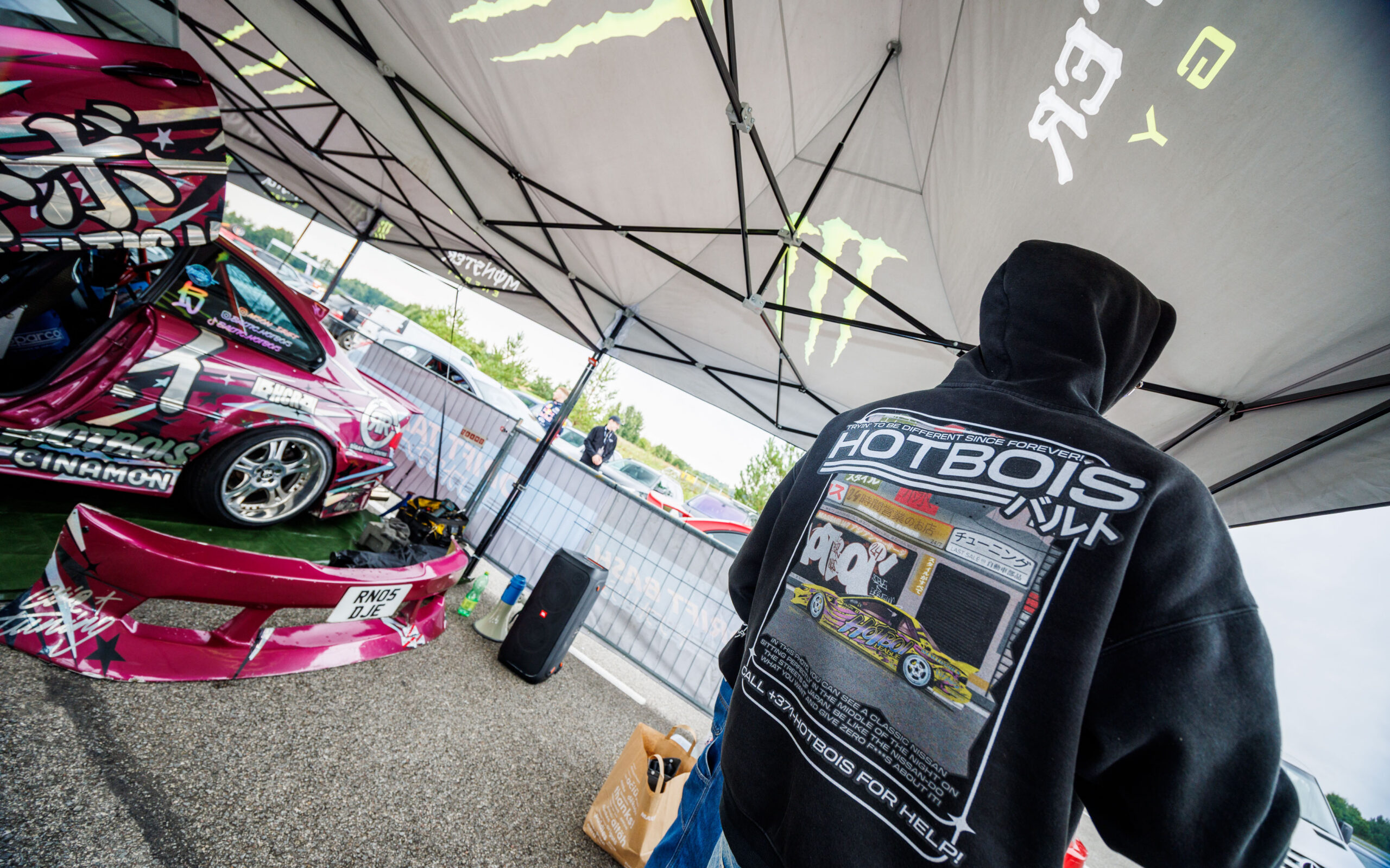 Hotbois pusaga mees vaatamas boksis seisvat lillakas-roosat driftiautot Pärnu Porsche Ringil Augustfest 2026 festivalil