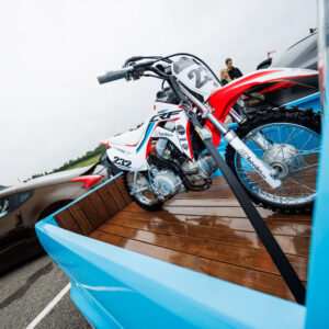 Helesinise kastiauto puidust kastis rihmadega kinnitatud punane-valge Honda CRF krossimootorratas Pärnu Porsche Ringil Augustfest 2026 festivalil