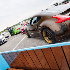 Pronksipruun Nissan 370Z tagavaates kuldse randiga valuvelgedega ja taustal teised tuuningautod Pärnu Porsche Ringil Augustfest 2026 festivalil