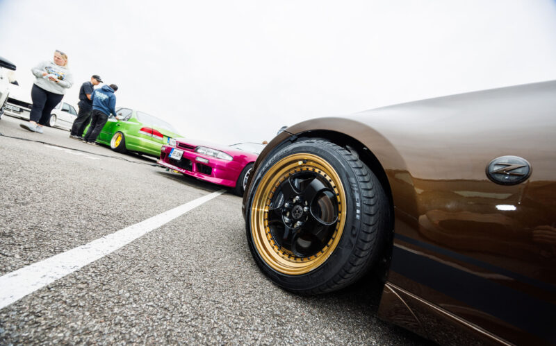 Pronksipruuni Nissan 350Z esitiib kuldse randiga mitmeosalise veljega taustal roosa Nissan Skyline ja roheline auto Pärnu Porsche Ringil Augustfest 2026 festivalil