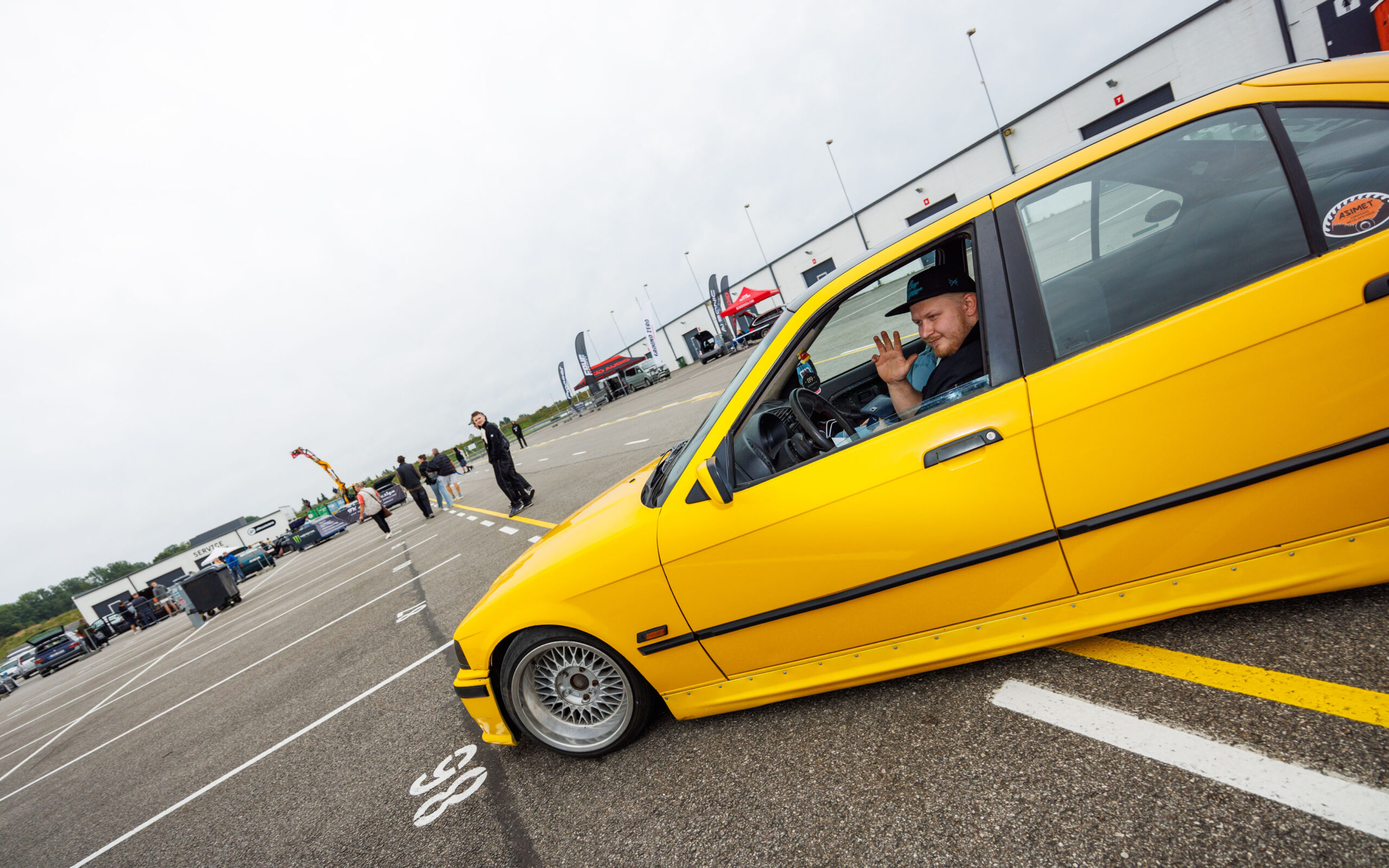 Madaldatud erekollane BMW E36 sedaan juht rooli taga lehvitamas Pärnu Porsche Ringil Augustfest 2026 festivalil