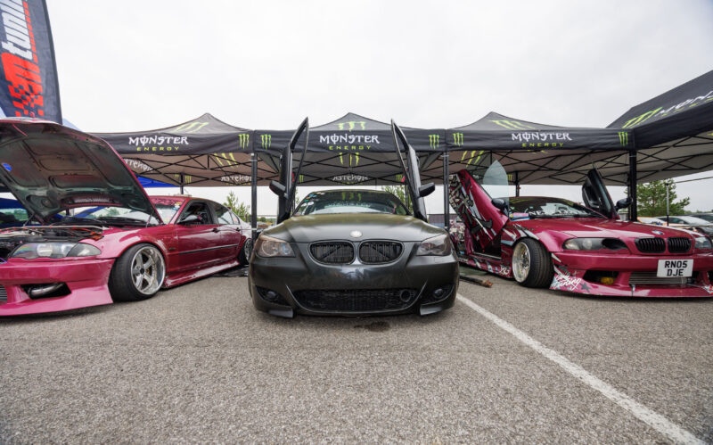 Tuunitud püstiste ustega mattmust BMW E60 ja kirsipunased BMW E46 projektiautod Monster Energy telkide all Pärnu Porsche Ringil Augustfest 2026 festivalil