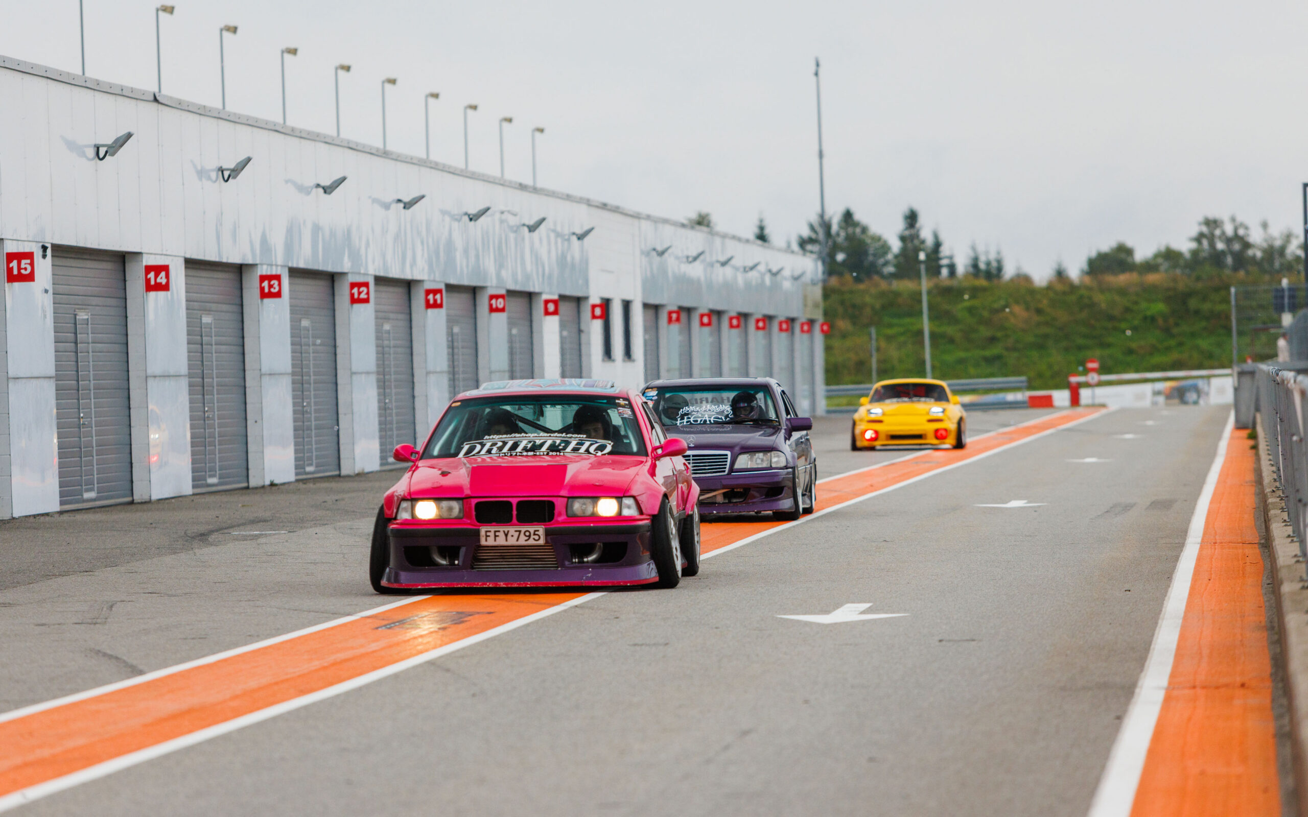Roosa BMW E36 driftiauto ja teised võistlusautod reas Pärnu Porsche Ringi boksiteel Augustfest 2026 festivalil